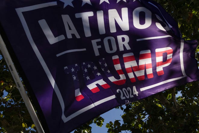 Apoiadores do candidato presidencial republicano Donald Trump seguram uma bandeira 'Latinos para Trump' antes de uma arrecadação de fundos que ele está realizando em Woodside, em Palo Alto, Califórnia, em 13 de setembro de 2024.