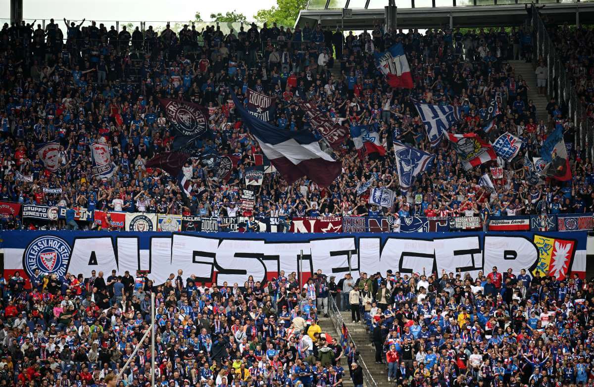 Torcedores do Holstein Kiel no jogo em Hannover 96 em 19 de maio de 2024 com um "Estrela em ascensão"-Bandeira.