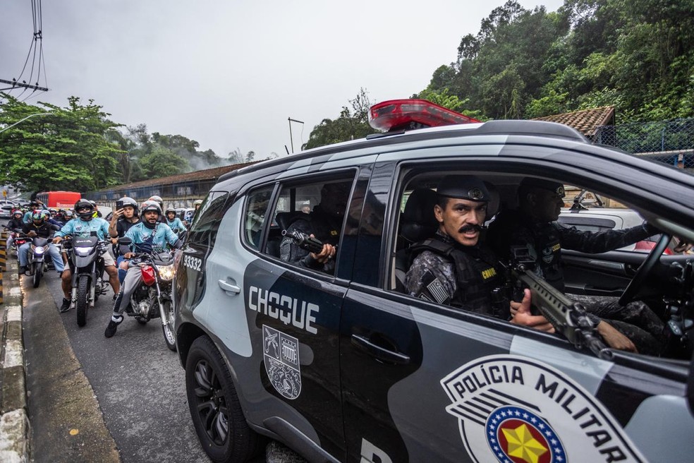 Policial militar aponta arma durante cobertura jornalística do velório do menino Ryan, morto pela PM em Santos, no litoral paulista — Foto: Maria Isabel Oliveira / O Globo