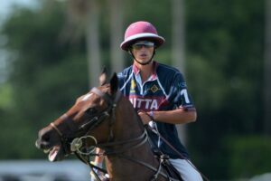 Um homem é visto cavalgando virando a cabeça para a direita com a boca aberta, o que parece ser uma partida de pólo.
