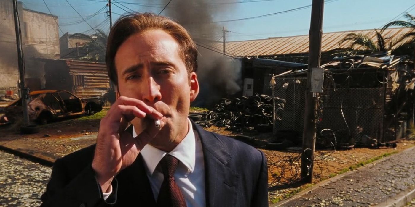 Nicolas Cage como Yuri Orlov fuma um cigarro em frente aos destroços fumegantes em Lord of War