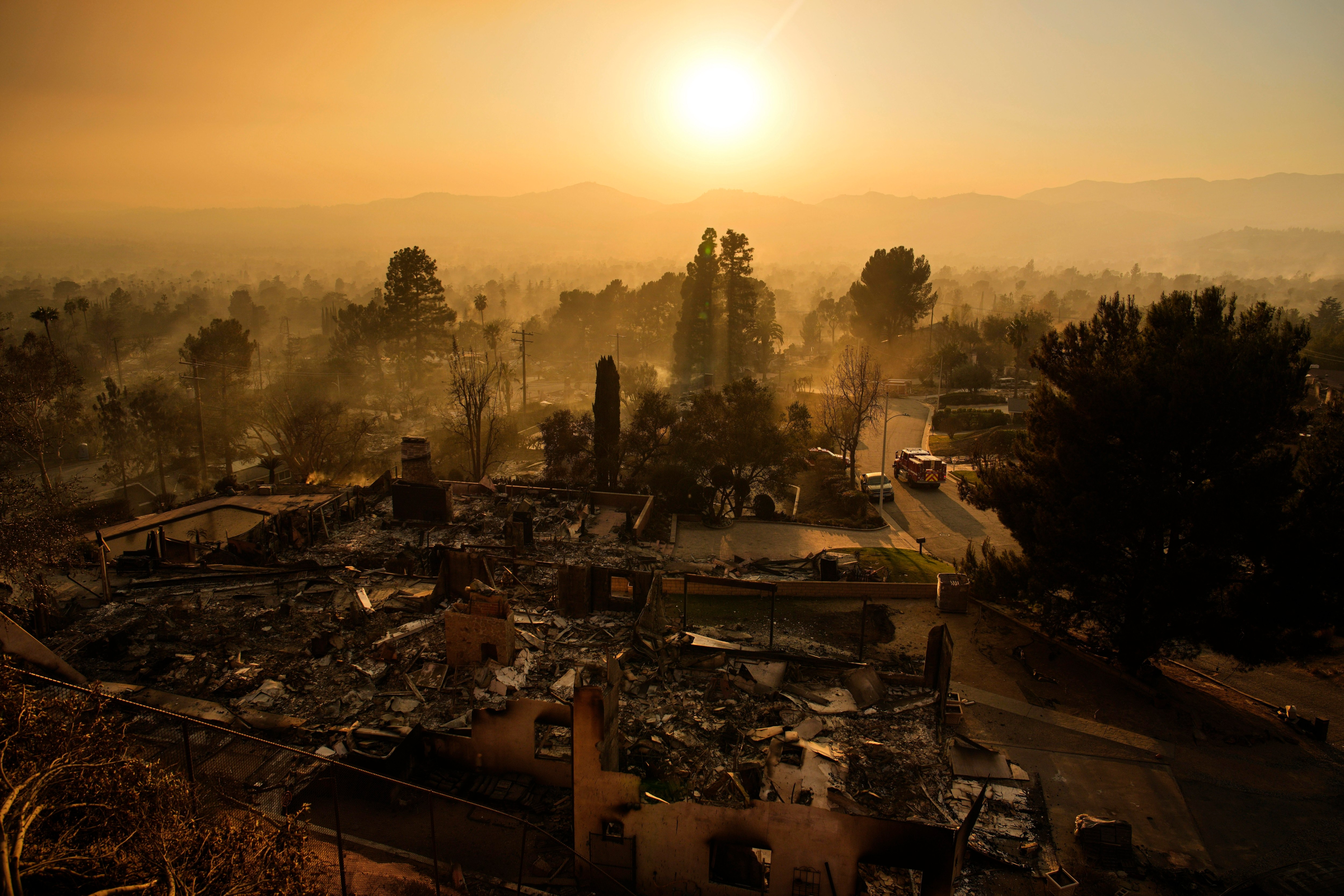 Bairro devastado pelo fogo em Altadena, Califórnia, com um veículo de emergência visível.