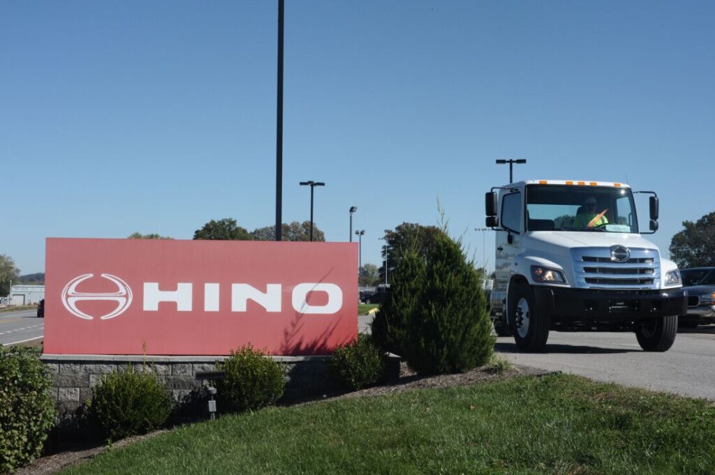 Um caminhão passa por uma placa da Hino em Williamstown, WV, em 2017. O fabricante do caminhão, uma subsidiária da Toyota, concordou em se declarar culpado de acusações federais de conspiração e pagar um total de US$ 1,6 bilhão para resolver ações civis depois que os reguladores descobriram que foram enviados dados fraudulentos para fugir aos padrões de emissões.