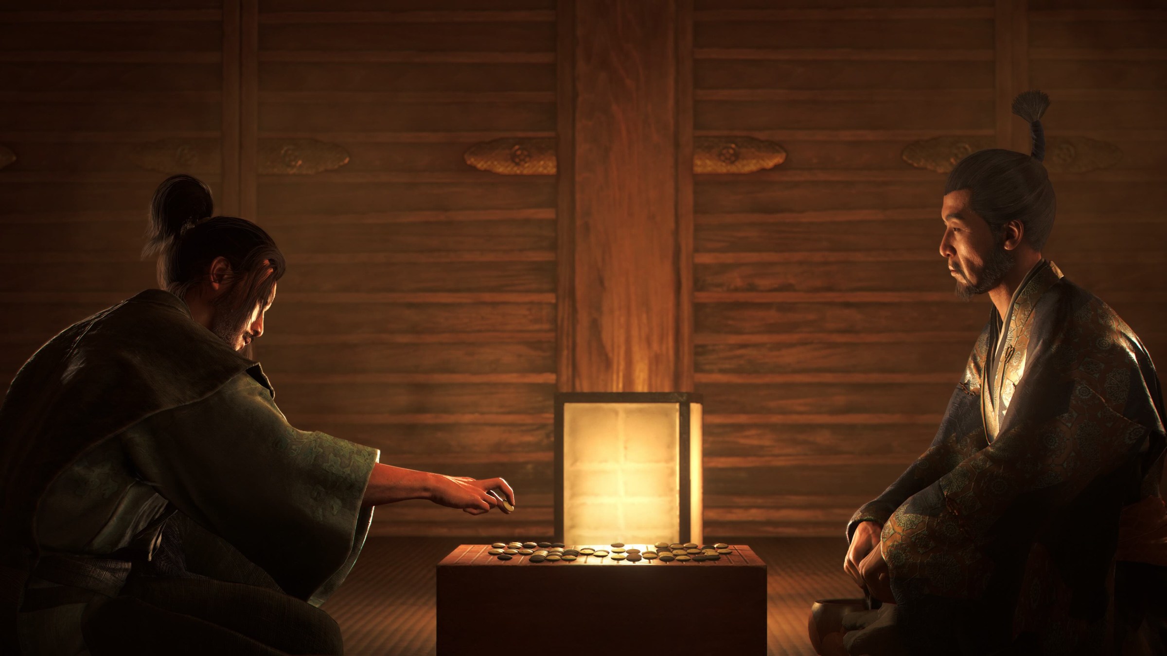 A prévia de Assassin's Creed Shadows mostra que os fãs de jogos AC esperaram 2 Dois personagens sentados em uma pequena mesa em uma sala mal iluminada em Assassin's Creed Shadows