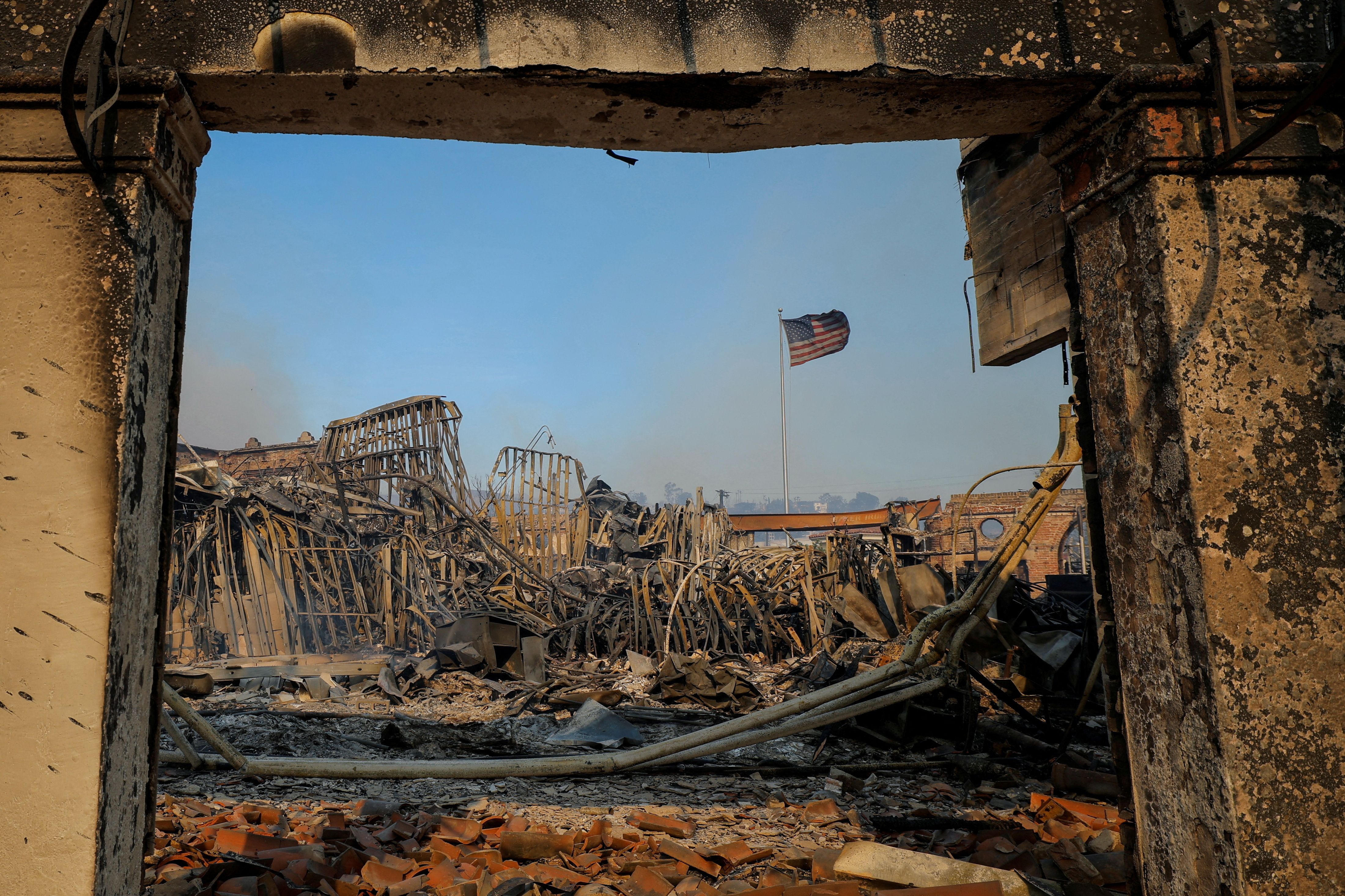 'Suspeito de incêndio criminoso' em Los Angeles é preso e número de mortos chega a dez 1 Uma bandeira dos EUA tremula sobre os restos de edifícios danificados pelo fogo em Los Angeles.